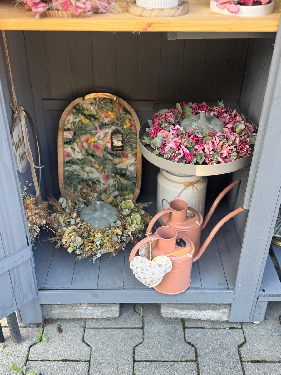 Marktstand-Regal mit Trockenblumenkränzen und Deko in Terracotta-Tönen