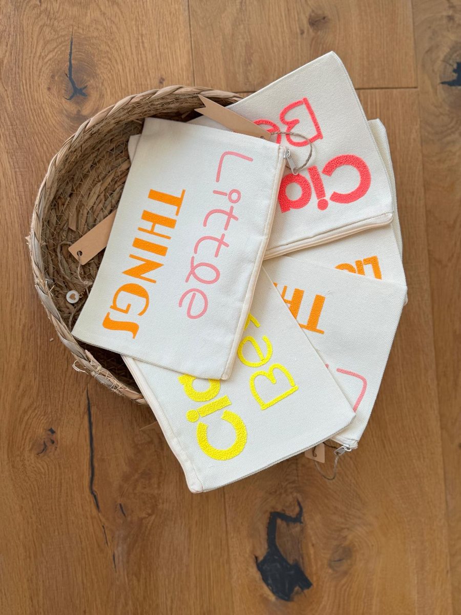Bunte Täschchen mit Aufschriften wie 'Little Things' und 'Ciao Bella' in einem Korb